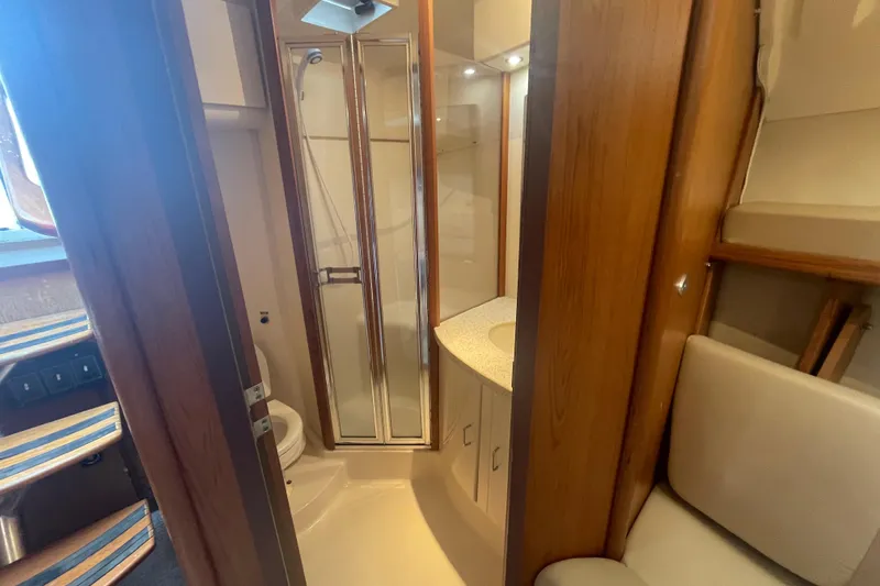 Slide: The Image of 1999 Luhrs 36 SX Open yacht bathroom with shower, sink, and wooden cabinetry. - 32