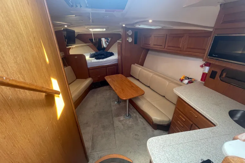 Slide: The Image of 1999 Luhrs 36 SX Open cabin interior with seating, table, and kitchenette. - 28