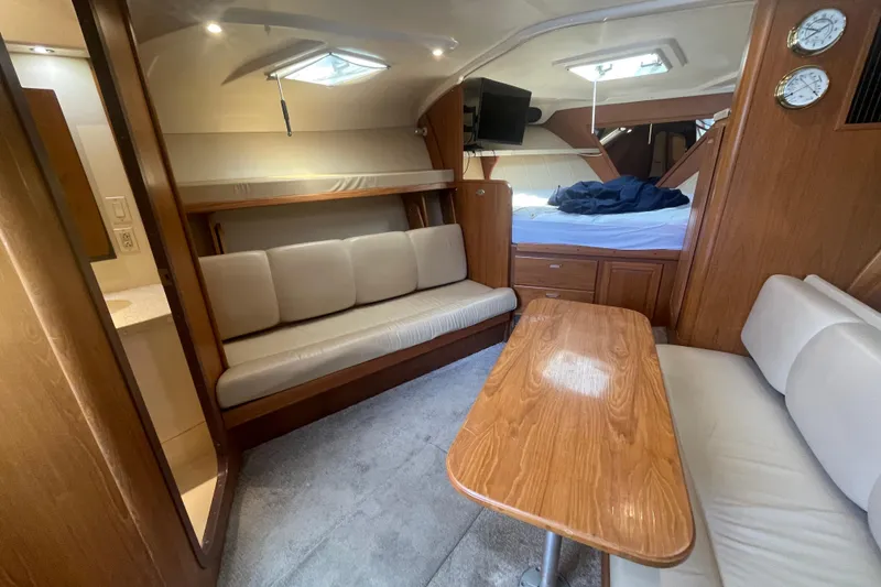 Slide: The Image of 1999 Luhrs 36 SX Open interior with cozy seating, wooden table, and natural light. - 30