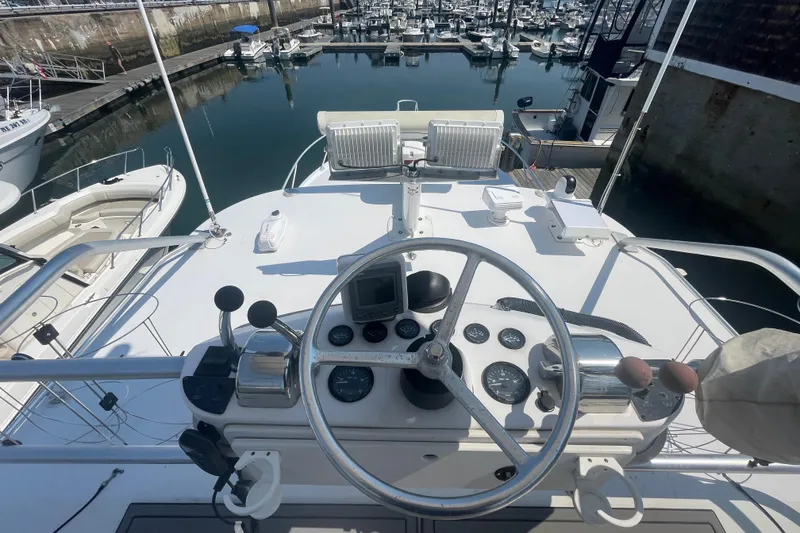 Slide: The Image of 1999 Luhrs 36 SX Open yacht helm with marina view, showcasing controls and steering wheel. - 39