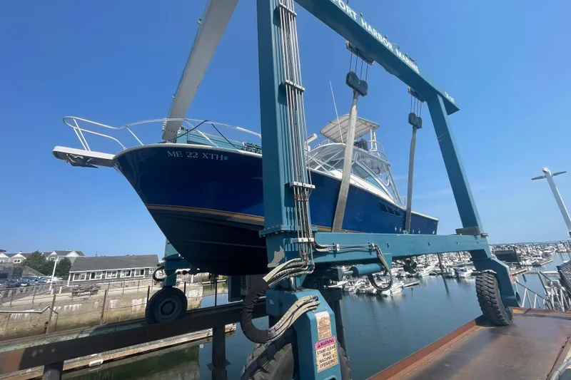 Slide: The Image of 1999 Luhrs 36 SX Open boat lifted at marina, clear blue sky background. - 45