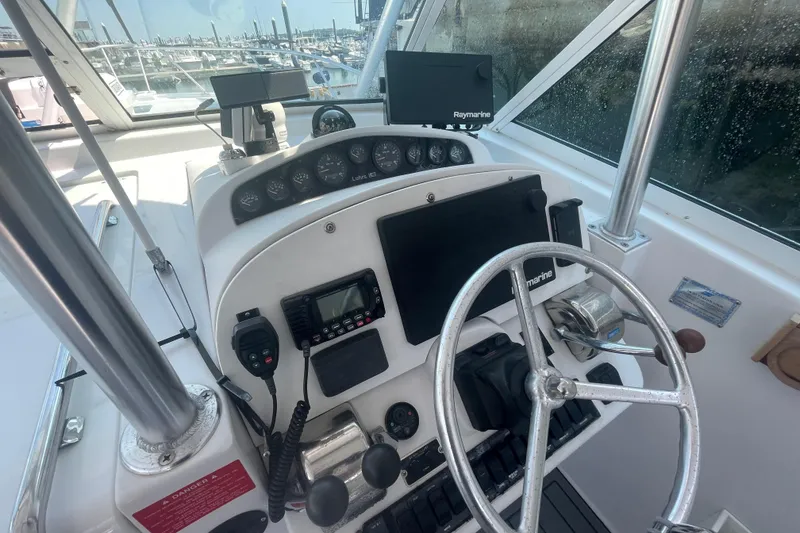 Slide: The Image of Control panel of a 1999 Luhrs 36 SX Open boat with steering wheel and navigation equipment. - 24
