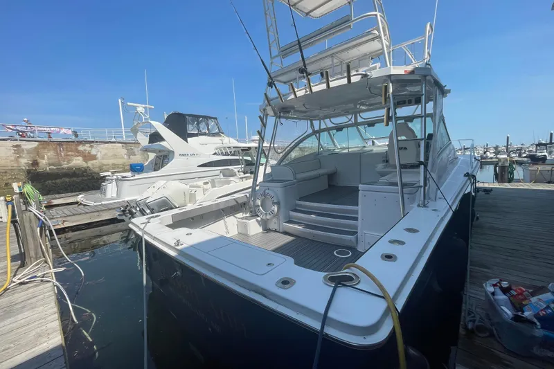 Slide: The Image of 1999 Luhrs 36 SX Open yacht docked at marina, showcasing spacious deck and seating area. - 8