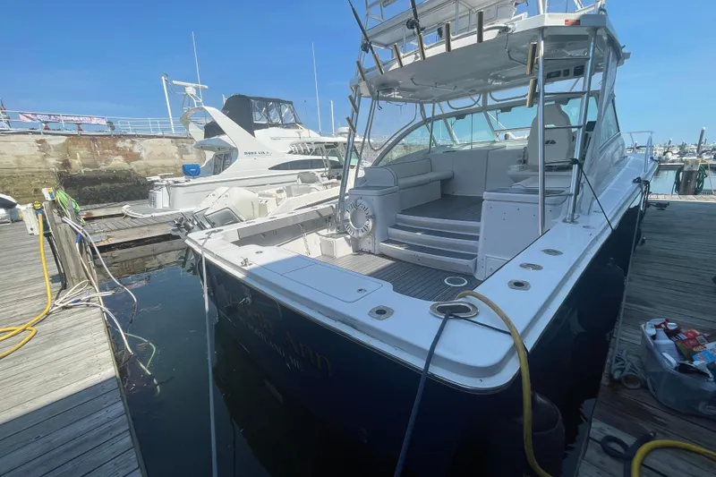Slide: The Image of 1999 Luhrs 36 SX Open yacht docked at marina, showcasing spacious deck and seating area. - 5