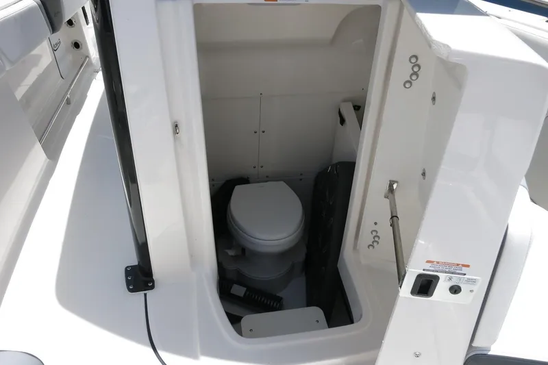 Slide: The Image of 2026 Robalo R270 Center Console boat interior with compact marine toilet. - 65