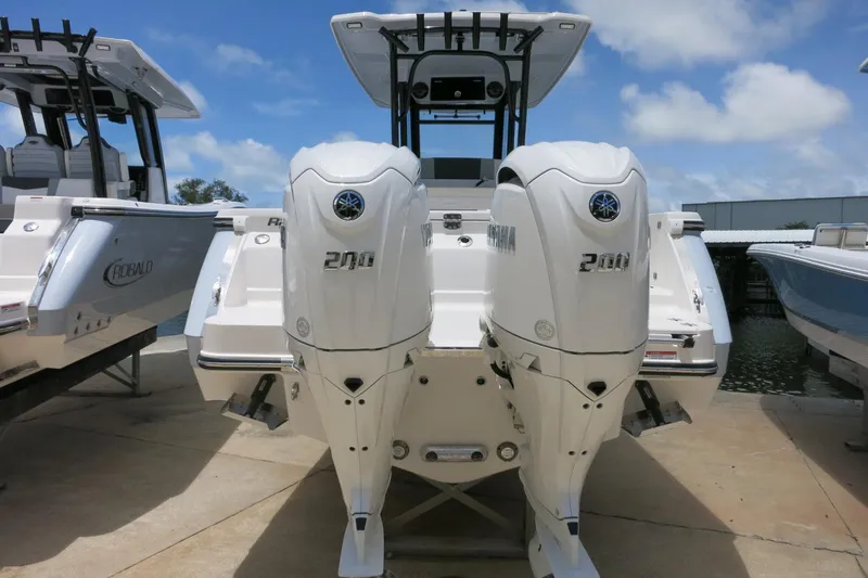 Slide: The Image of 2026 Robalo R270 Center Console boat with dual Yamaha 200 engines, docked under blue sky. - 7