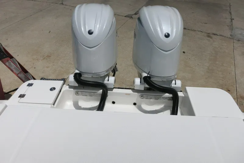 Slide: The Image of Twin outboard engines on a 2026 Robalo R270 Center Console boat, docked on concrete. - 36