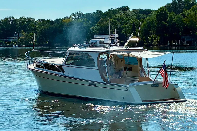 Slide: The Image of 2005 Marlow 375 boat cruising on a serene lake with American flag. - 49