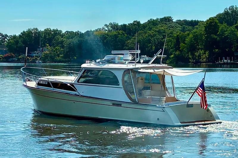 Slide: The Image of A 2005 Marlow 375 boat cruising on a serene lake with lush green trees. - 50
