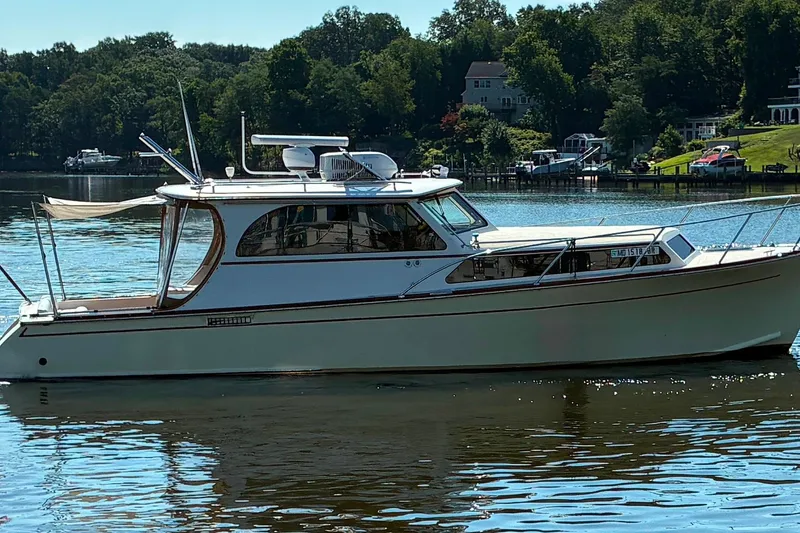 The Image of 2005 Marlow 375 boat on a serene lake with lush green surroundings. - 0