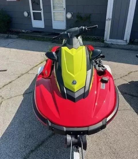 Slide: The Image of A red and yellow jet ski sits on a trailer in front of a gray building. - 2