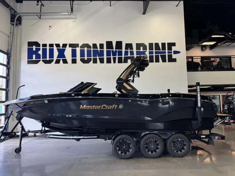 Slide: The Image of A black 2025 MasterCraft X24 boat is in a showroom with "Buxton Marine" on the wall. - 4