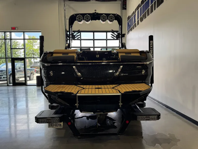 Slide: The Image of A 2025 MasterCraft X24 in a showroom. The boat features a black exterior and wooden platform. - 6