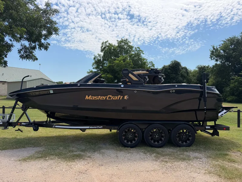 The Image of A 2025 MasterCraft X24 boat on a trailer outdoors. - 1