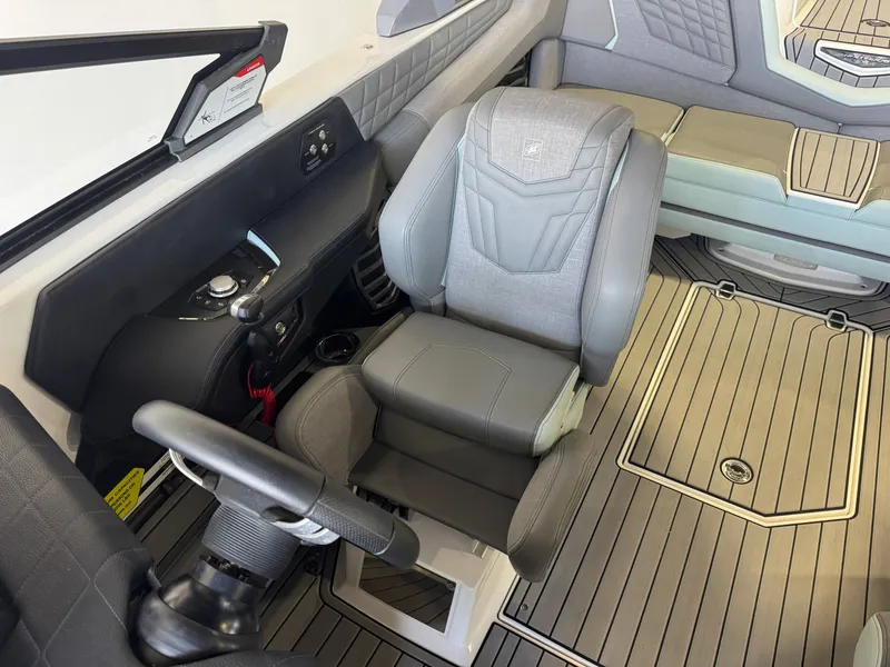 Slide: The Image of The image shows the interior of a 2022 Nautique Super Air Nautique G21 with gray upholstery and a modern helm. - 21