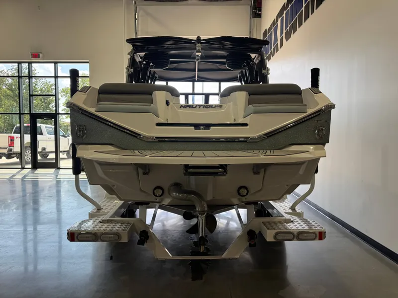 Slide: The Image of The image shows the rear of a 2022 Nautique Super Air Nautique G21 boat in a showroom. - 6