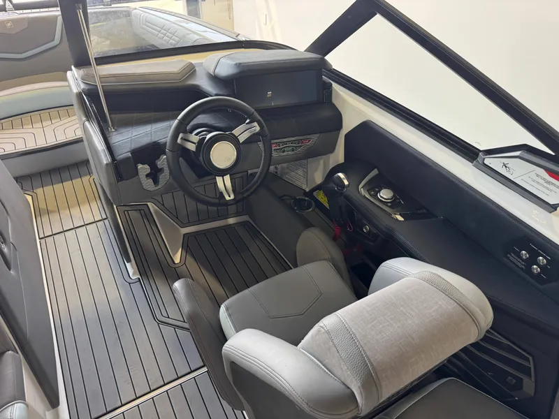 Slide: The Image of The image shows the cockpit of a 2022 Nautique Super Air Nautique G21 with a modern steering wheel and gray seats. - 25