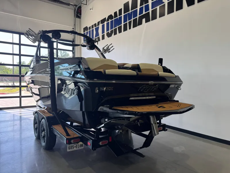 Slide: The Image of A black 2021 Tigé 25ZX boat on a trailer inside a showroom. - 5