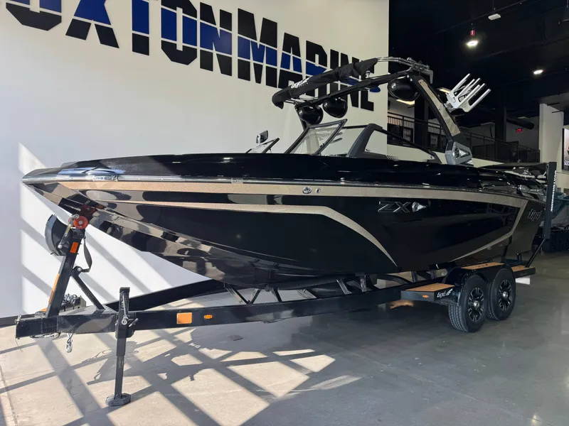 Slide: The Image of A black 2021 Tigé 25ZX boat on a trailer in a showroom. - 2