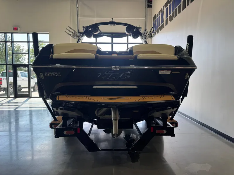 Slide: The Image of Rear view of a 2021 Tigé 25ZX boat in a showroom, featuring two seats and a tower. - 6