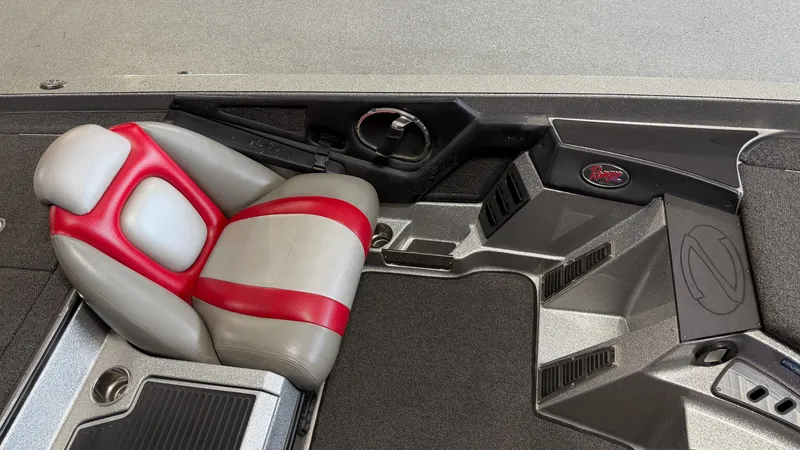 Slide: The Image of The interior of a 2015 Ranger Tugs Z520C features a gray and red seat with modern controls. - 34