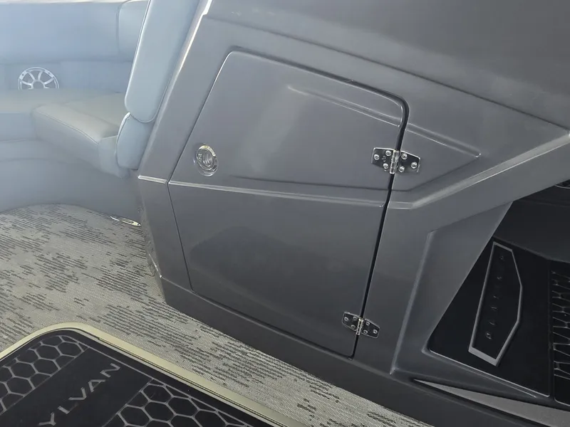 Slide: The Image of The image shows the interior of a 2027 Sylvan G-3 SLZ boat with gray upholstery and a storage compartment. - 28