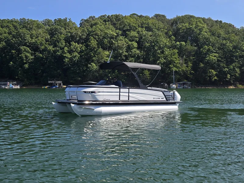 Slide: The Image of A 2027 Sylvan G-3 SLZ pontoon boat on a calm lake with a wooded shoreline. - 36