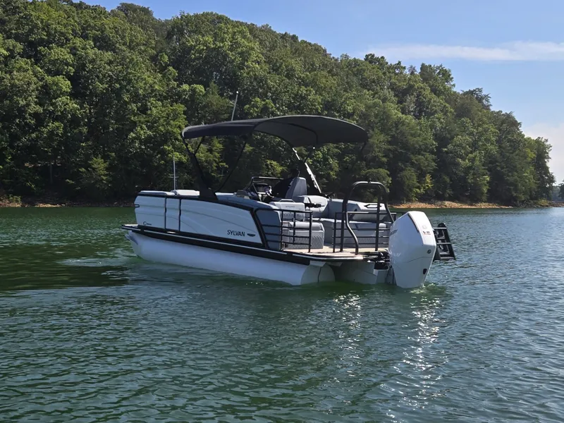 Slide: The Image of A modern Sylvan pontoon boat, model G-3 SLZ, on a calm lake with a wooded shoreline. - 40