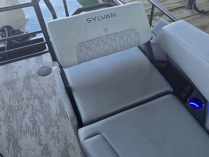 Slide: The Image of The image shows a gray lounging area on a Sylvan boat, surrounded by blue cup holders. - 11