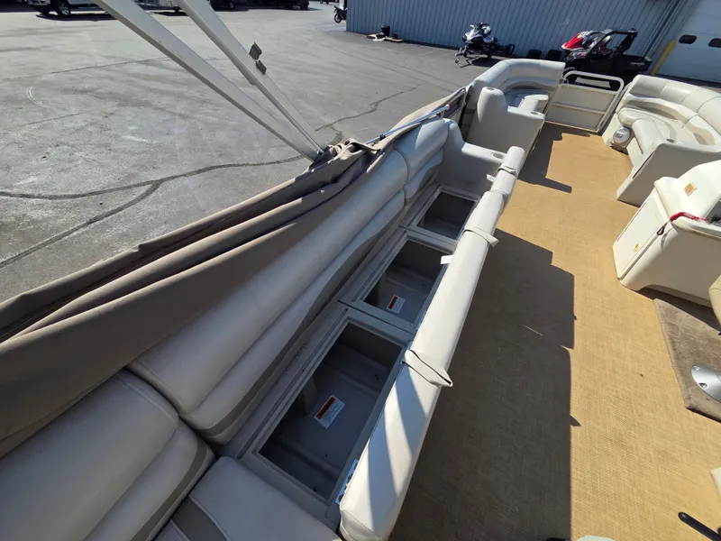 Slide: The Image of The image shows the interior of a 1998 Sylvan 826 Nexus pontoon boat with beige seating and storage. - 21