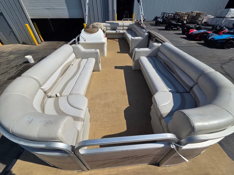 Slide: The Image of A spacious pontoon boat with beige upholstery and an open deck layout, situated in a warehouse. - 11