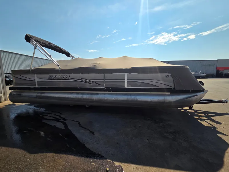 Slide: The Image of A 1998 Sylvan 826 Nexus pontoon boat with a cover, parked on a concrete surface. - 5
