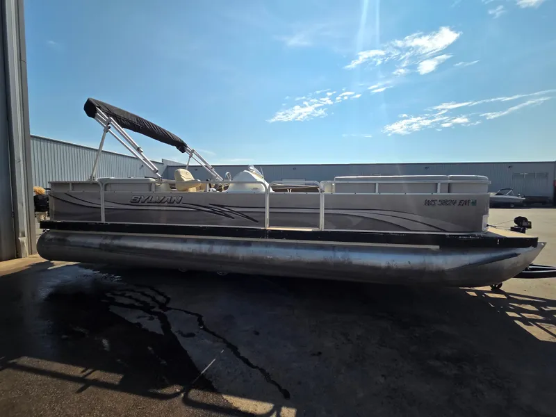 Slide: The Image of A 1998 Sylvan 826 Nexus pontoon boat is parked on a dry lot. It features a black canopy. - 6