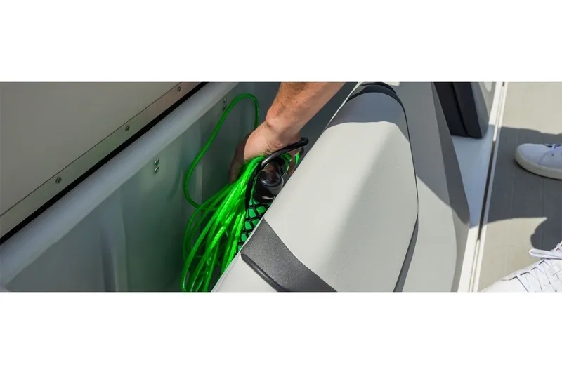 Slide: The Image of A person stores a green rope in a storage compartment on a boat. - 10