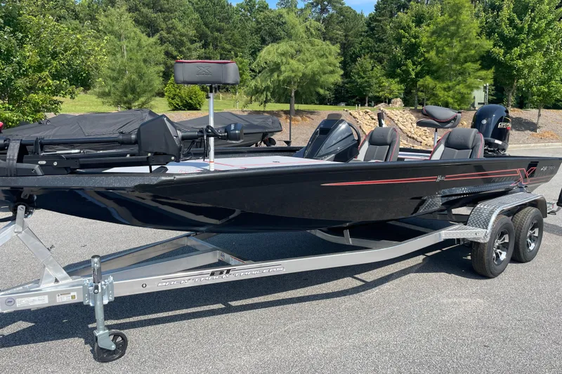 Slide: The Image of 2027 Xpress H20 Bass boat on trailer, parked outdoors with trees in background. - 7