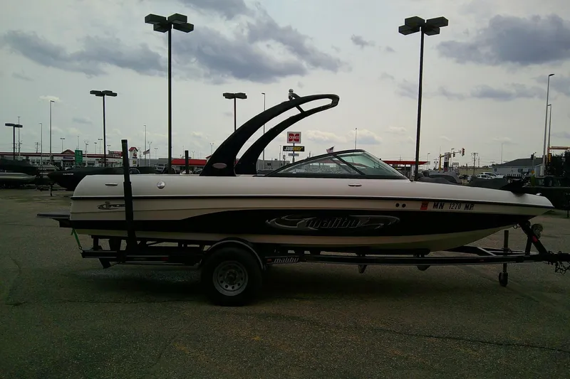Slide: The Image of 2005 Malibu iRide boat on trailer in parking lot under cloudy sky. - 4