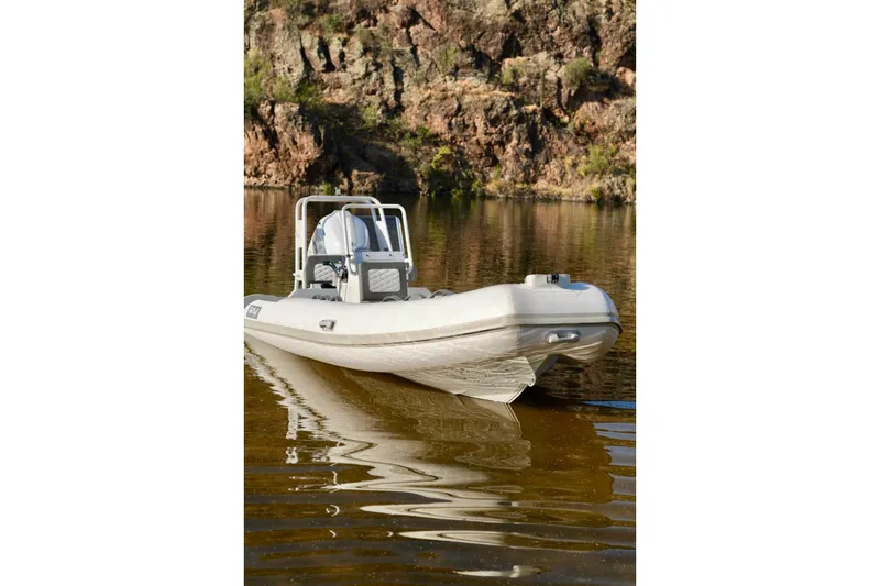 Slide: The Image of 2027 Tide Craft Kodiak 16 boat on calm water with rocky background. - 11