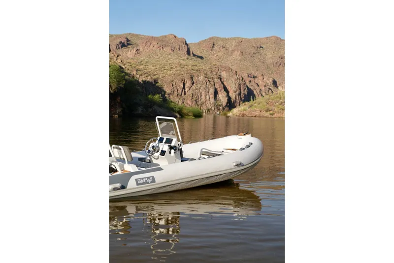 Slide: The Image of Tide Craft Kodiak 16 boat on a serene lake with rocky hills in the background, 2027 model. - 3