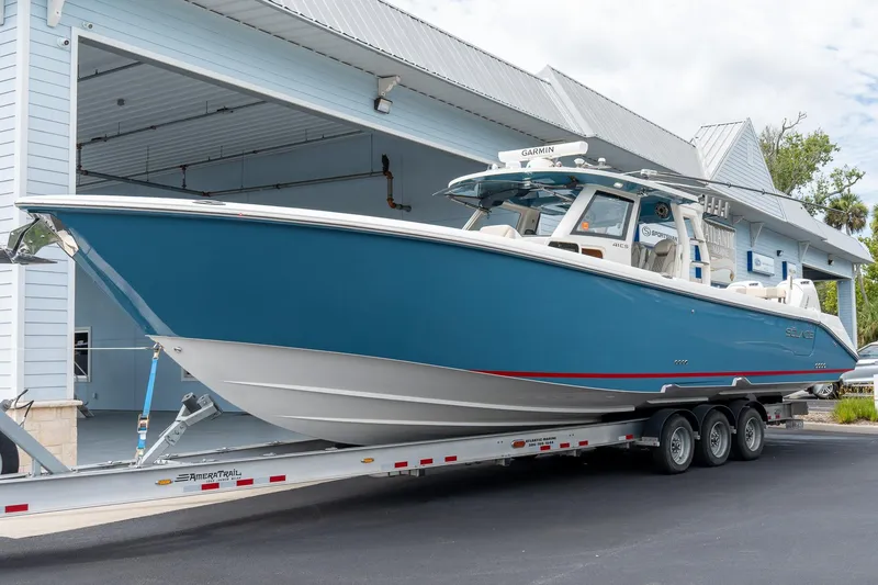 Slide: The Image of 2023 Solace 41CS boat on trailer, blue hull, parked outside a building. - 9