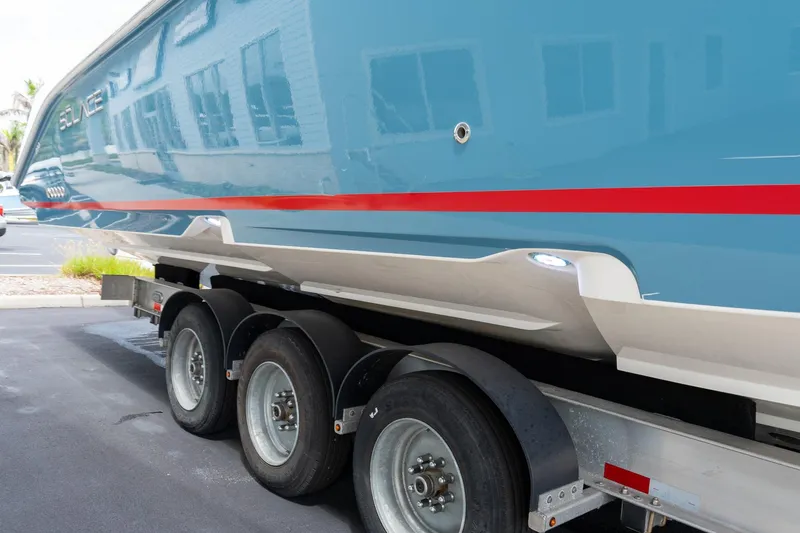 Slide: The Image of 2023 Solace 41CS boat on trailer, showcasing sleek blue hull with red stripe. - 24