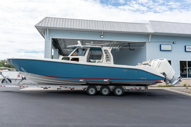 Slide: The Image of 2023 Solace 41CS boat on trailer outside a blue building. - 8