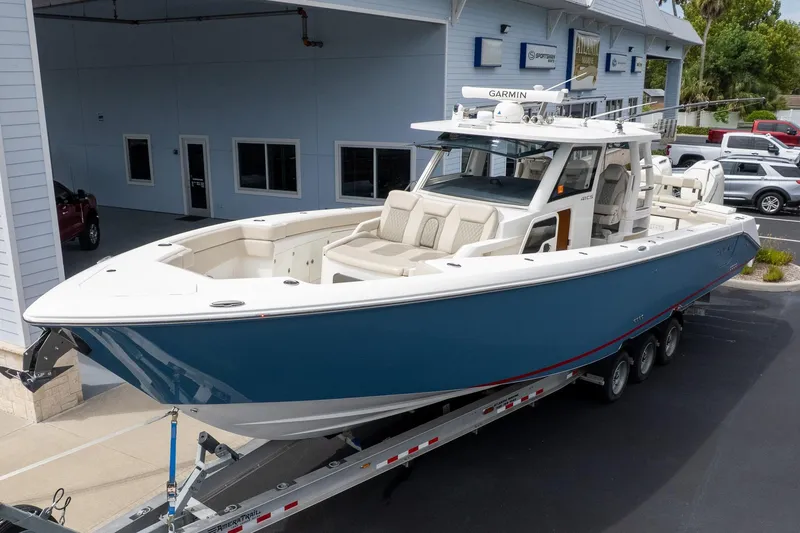 The Image of 2023 Solace 41CS boat on trailer, blue hull, parked outside dealership. - 0