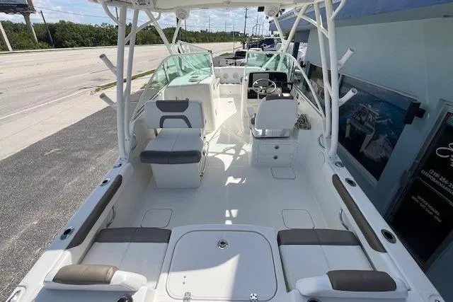 Slide: The Image of 2019 World Cat 230 DC boat interior with seating and helm, docked near a road. - 8