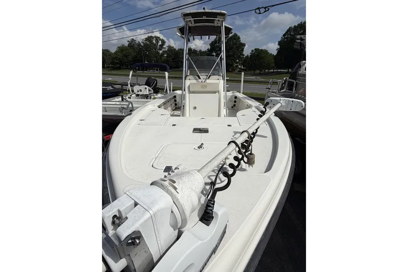 Slide: The Image of 2003 Triton 220 LTS boat with trolling motor, parked outdoors under clear skies. - 4