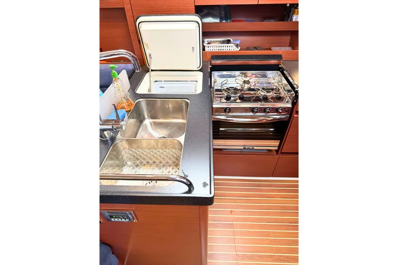 Slide: The Image of The galley of a 2020 Hanse 458 with a sink, stove, and wooden flooring. - 18