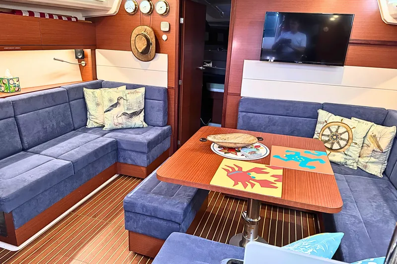 Slide: The Image of Luxurious 2020 Hanse 458 yacht interior with blue seating, wooden table, and nautical decor. - 16
