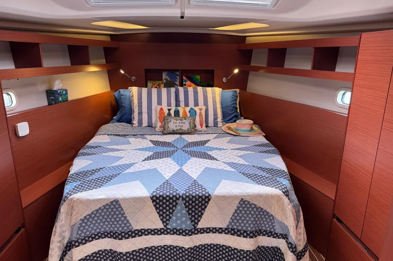 Slide: The Image of Cozy cabin interior of 2020 Hanse 458 yacht with patterned bedding and wooden shelves. - 25