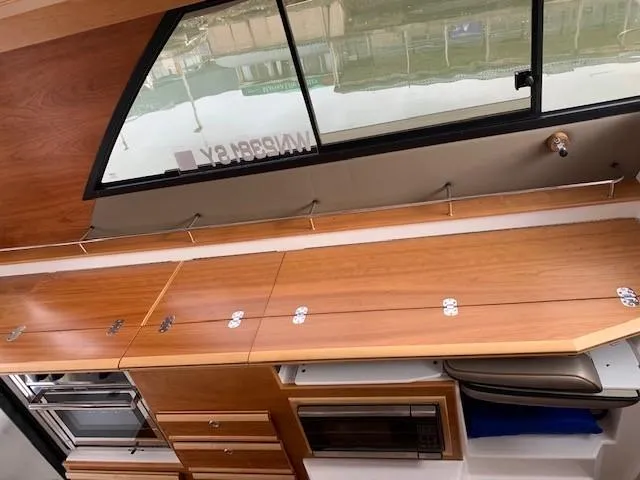 Slide: The Image of Interior view of a 2021 Cutwater C-32 Coupe with wooden cabinets and a window. - 18