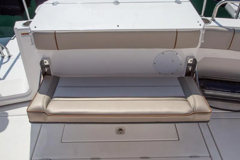 Slide: The Image of The rear bench seat of a 2021 Cutwater C-32 Coupe with beige upholstery and storage underneath. - 7