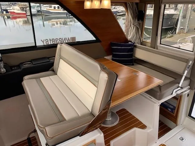 Slide: The Image of Interior of a 2021 Cutwater C-32 Coupe with cushioned seating and a wooden table. - 15